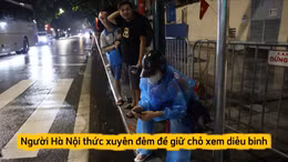 Ngưởi dân mặc áo mưa, che ô... giữ chỗ chờ xem diễu binh tối ngày 27/8.